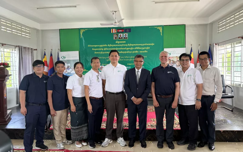 A group of people standing in front of a banner, smiling. 