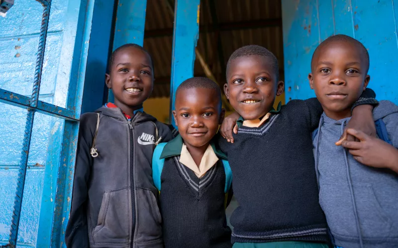 Four kids looking at the camera and smiling. 
