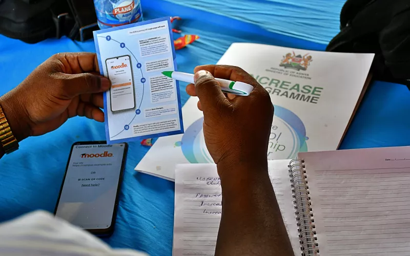 A person holds a brochure with a pen on a blue surface.