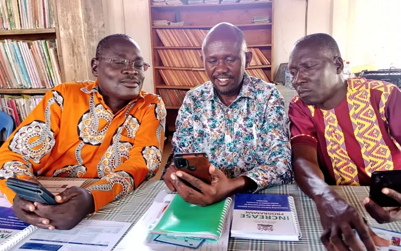Three men looking at a phone.