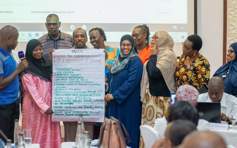 A group of people holding a banner with writing on it. 