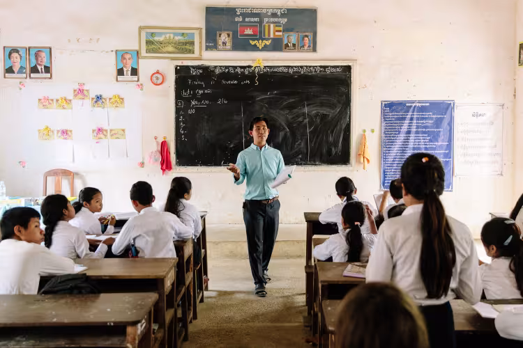 Teacher in Cambodia in front of a classroom