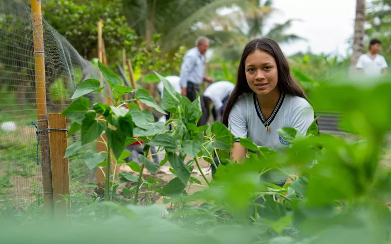 A student in Ecuador looks at the camera while tending to an agricultural project