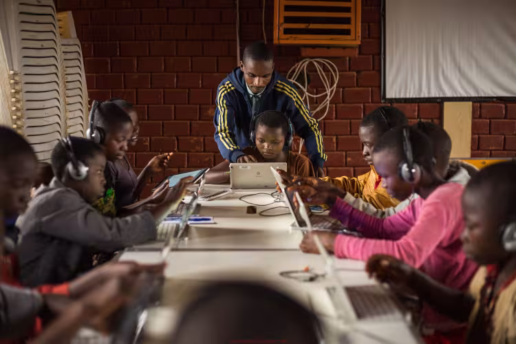 Children surfing on tablets, under the guidance of Alexis Nimubona, the facilitator in charge of the Ideas Box at the center. Credit: Kibuuka Mukisa Oscar / AFD
