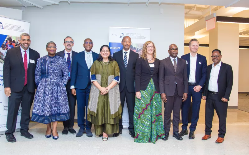 A group of ten people in professional attire standing together and smiling for a photo at an event.