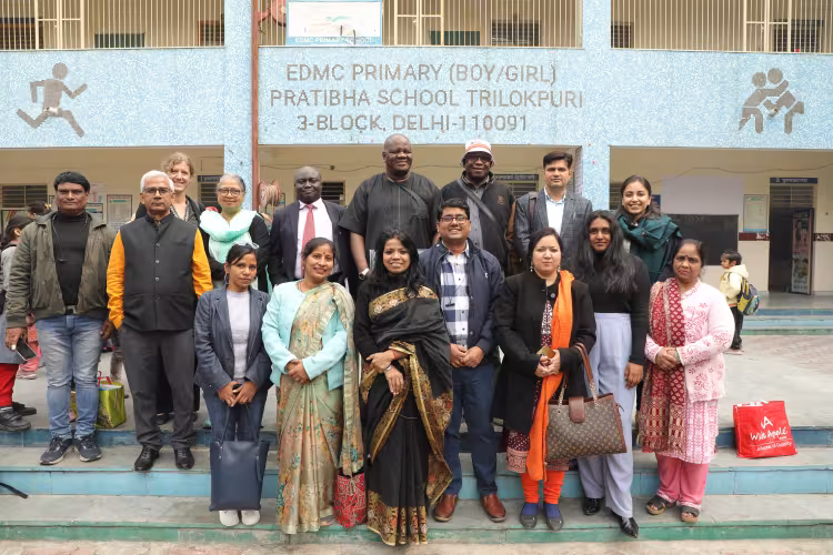 Group photo of people standing outside a school in Delhi, India.