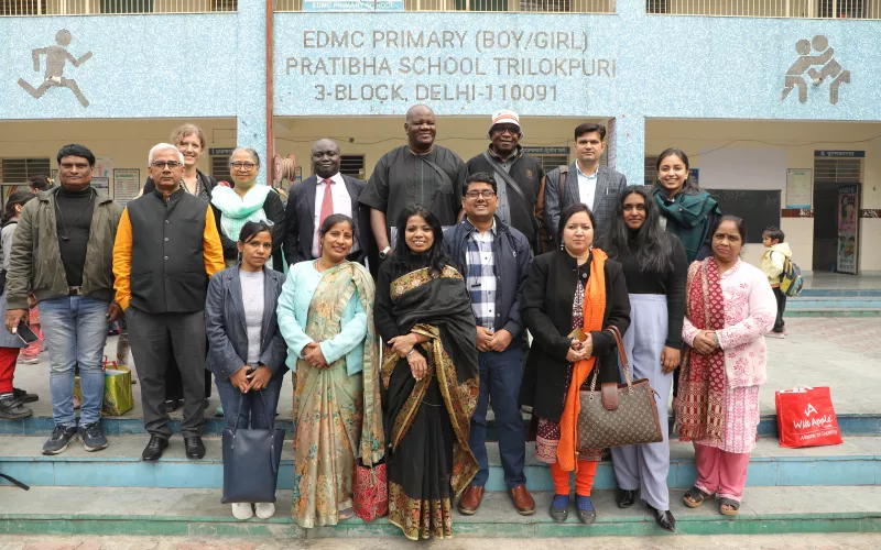 Group photo of people standing outside a school in Delhi, India.