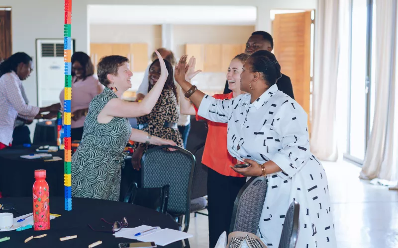 Participants share a high-five during a playful workshop activity with colourful building blocks.