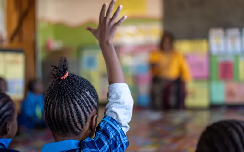 A schoolgirl raises her hand in a classroom in Zambia