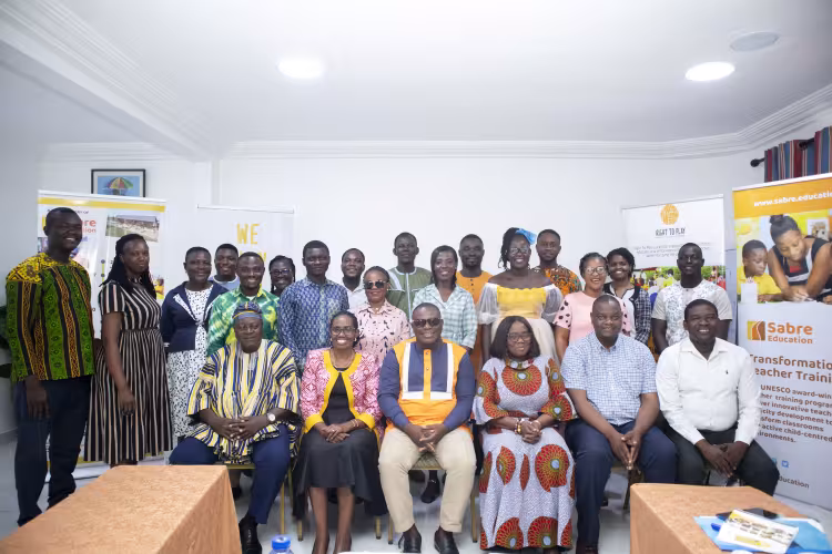 Group photo of educators and community leaders posing indoors at a professional development event, with banners for Sabre Education and Right to Play displayed in the background.