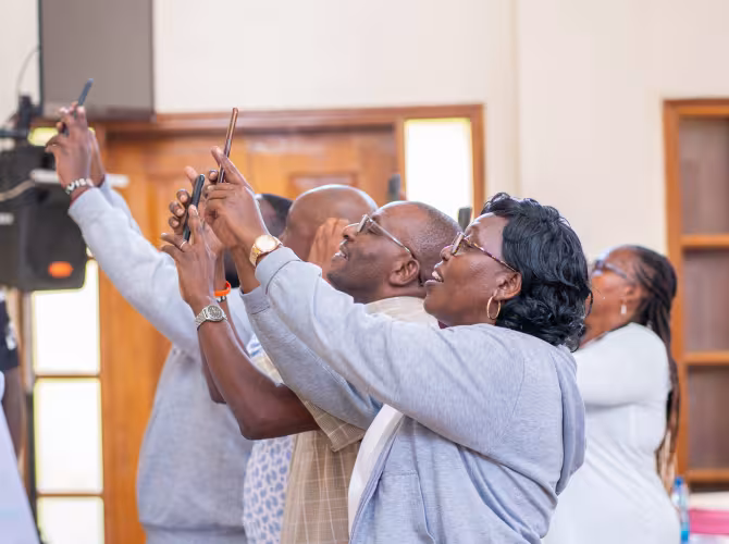 A group of workshop participants hold up their phones during an interactive activity.