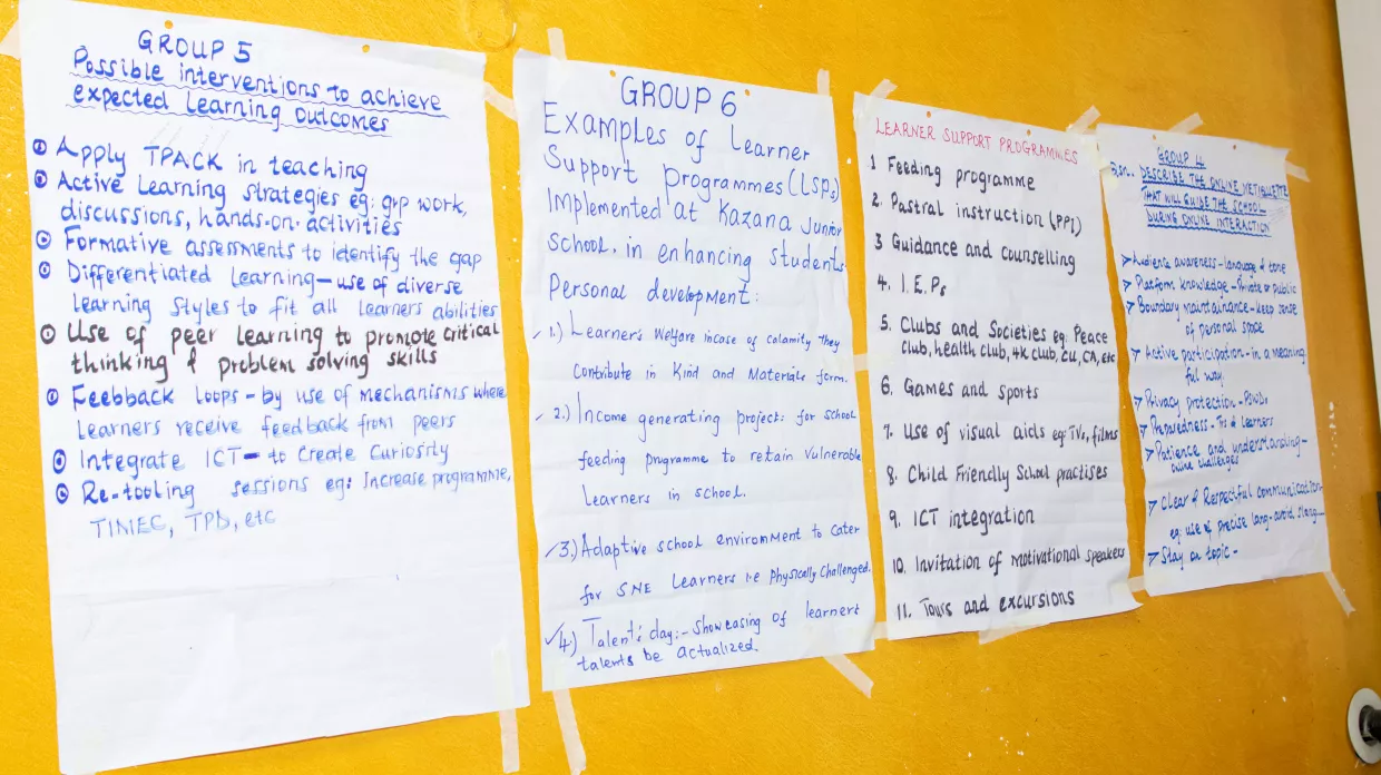 Showcase of large papers with writing stuck to the wall. 