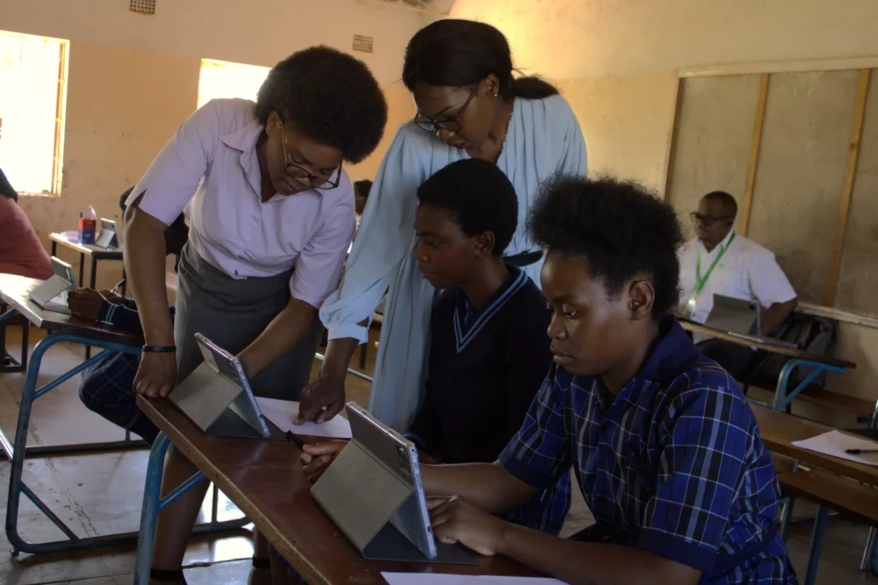 Teachers assist students using tablets during a classroom lesson.