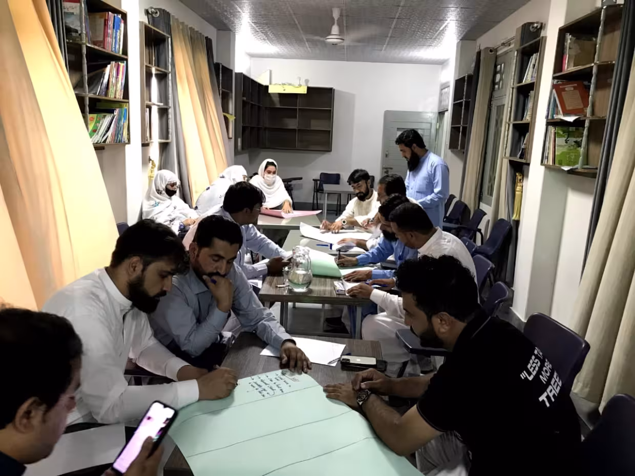 A group of men sit a tables and look at their phones.