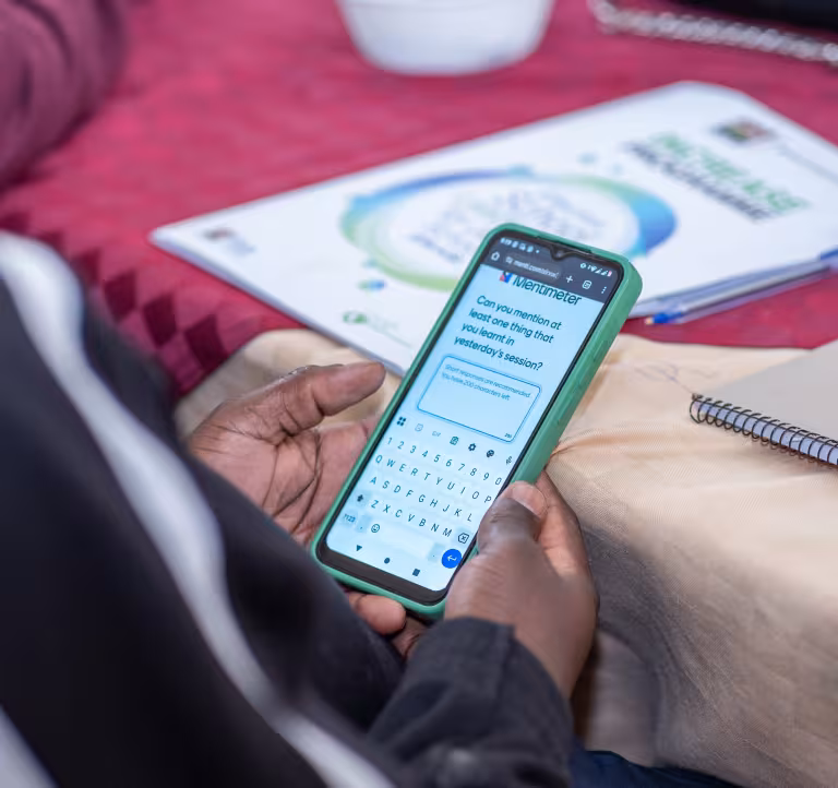 A workshop participant uses a smartphone to respond to an interactive Mentimeter question during a training session.
