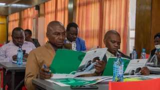 Four men reading a booklet.