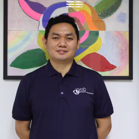 Roger wearing a navy VVOB polo shirt, standing in front of a colourful abstract painting.