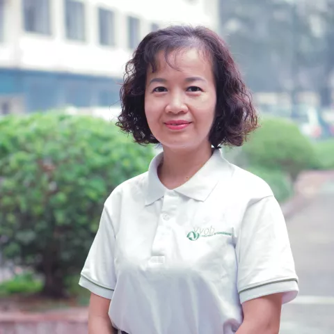 Hang smiles in a white VVOB polo shirt and stands outdoors. 