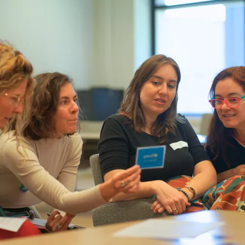 Four women looking at a blue card and discussing.