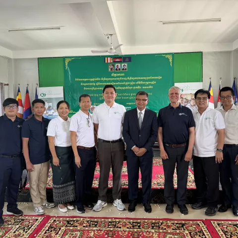 A group of people standing in front of a banner, smiling. 