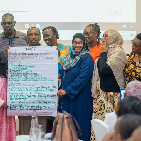 A group of people holding a banner with writing on it. 