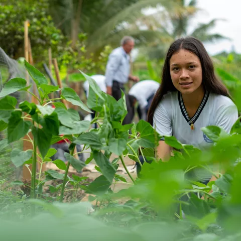 A student in Ecuador looks at the camera while tending to an agricultural project