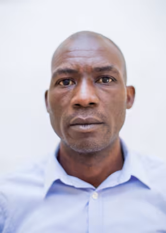 Charles is wearing a blue shirt. The background is plain white.