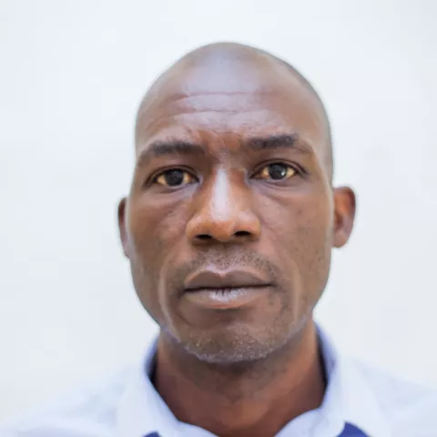 Charles is wearing a blue shirt. The background is plain white.