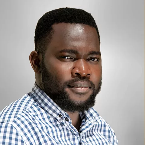 Clinton wears a blue and white checkered shirt. He is set against a neutral gray background.