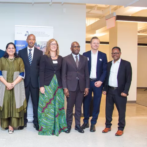 A group of ten people in professional attire standing together and smiling for a photo at an event.