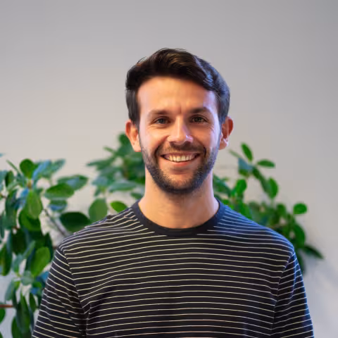 Dimitrios is smiling, a plant behind him.