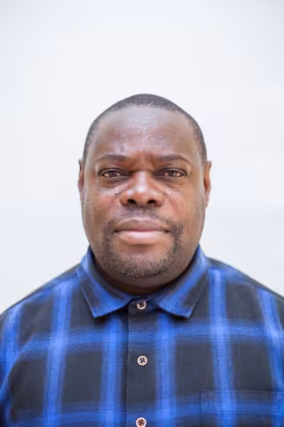 Elijah is wearing a blue checkered shirt against a plain white background. 