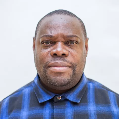 Elijah is wearing a blue checkered shirt against a plain white background. 