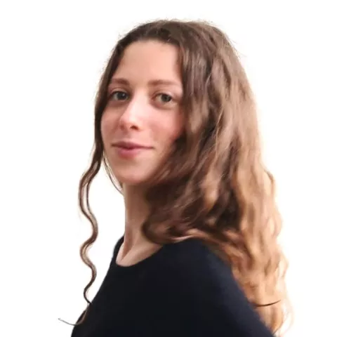 Liselotte is wearing a black shirt and smiling in front of a white background.