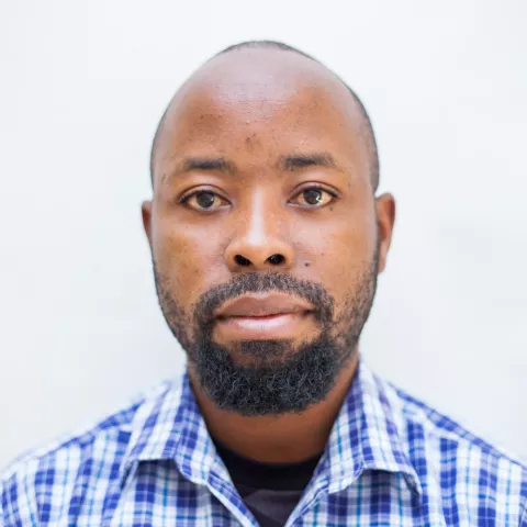 Frank is wearing a checkered shirt. The background is plain white.