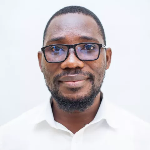 Morgan is wearing glasses and a white shirt. The background is plain white.