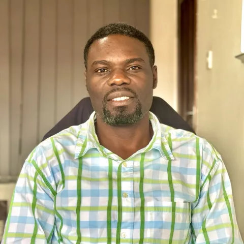Steven is wearing a blue and green plaid shirt. He's sitting in an indoor setting with soft lighting.